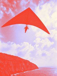 Hang glider flying above a mountain ridge.
